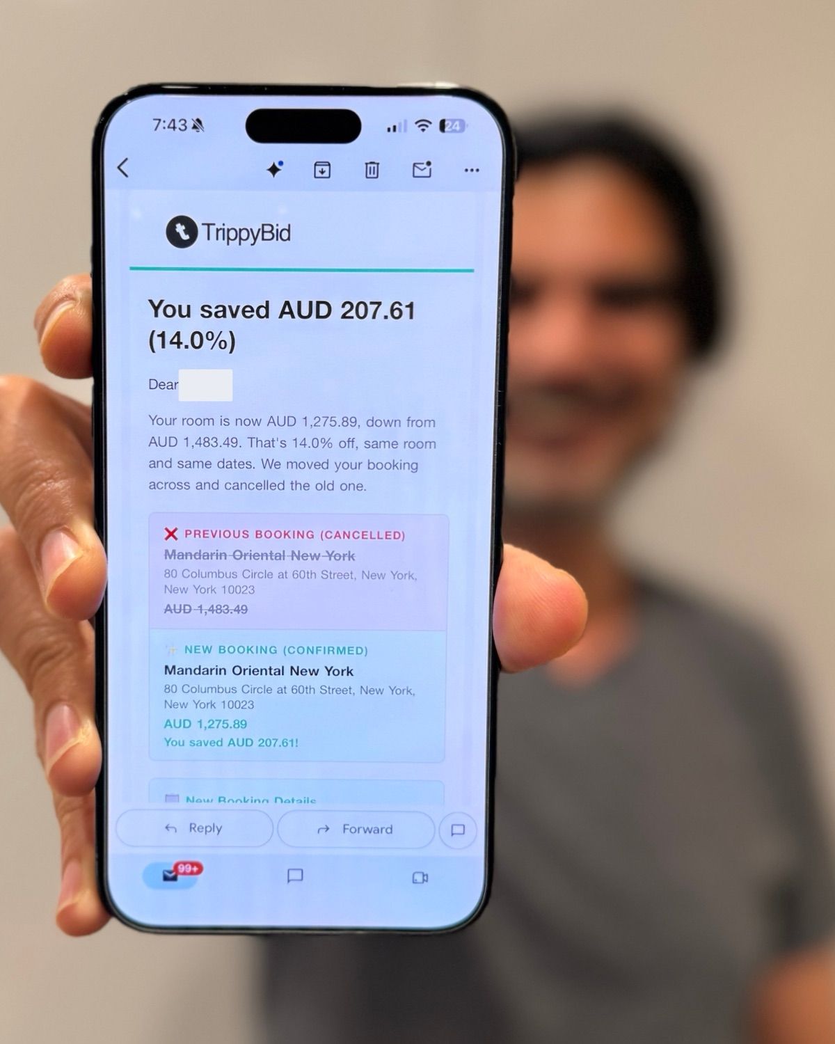 Nadeem, TrippyBid's founder, holding a phone showing a TrippyBid email: Mandarin Oriental New York rebooked from AUD 1,483.49 to AUD 1,275.89